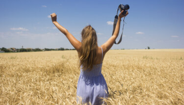 image of video creator in a golden field under a blue sky raising her hands in triumph